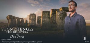 Dan Snow seen in front of a sunlit Stonehenge