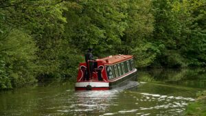 Red barget with black hull on a canal with trees behind